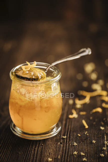 Orange marmalade with orange zest in a glass jar on a wooden background — Stock Photo