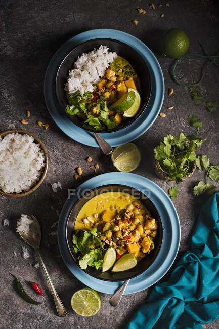 Curry tailandés vegetariano con calabaza y garbanzos, lima, cilantro y cacahuetes tostados - foto de stock
