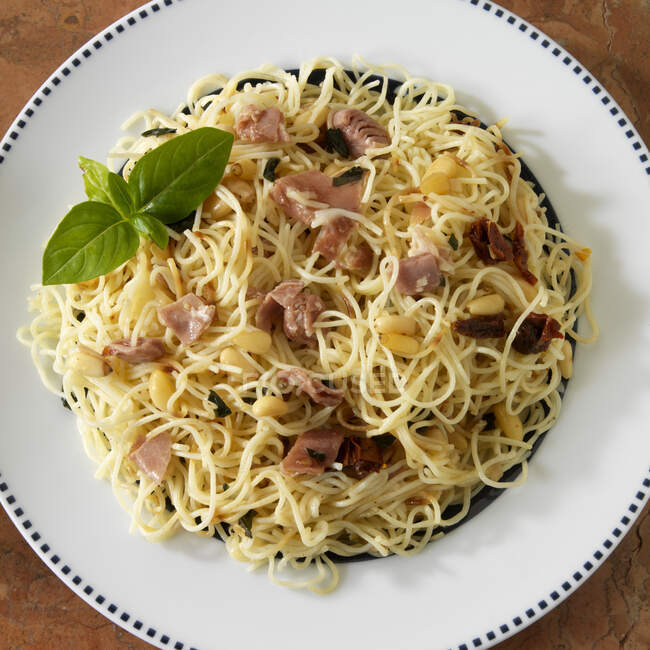 Angel hair pasta with prosciutto, pine nuts and basil — Stock Photo