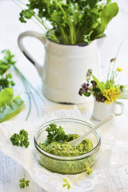 Pesto hecho de varias hierbas en el vaso, en la jarra de fondo con paquete de hierbas - foto de stock
