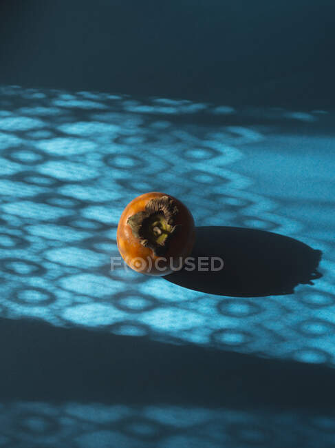 Still life with a persimmon on blue background — Stock Photo