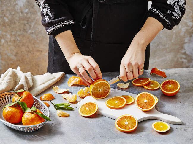 Una mujer rebanando naranjas de sangre - foto de stock