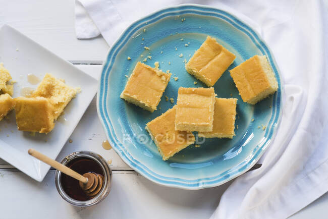 Кукурузный хлеб на голубой тарелке и мёд — стоковое фото