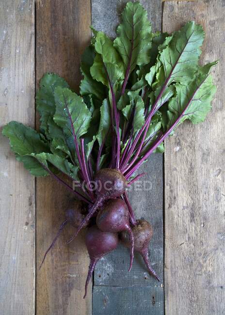 Several fresh beetroots with leaves on a wooden background — Stock Photo