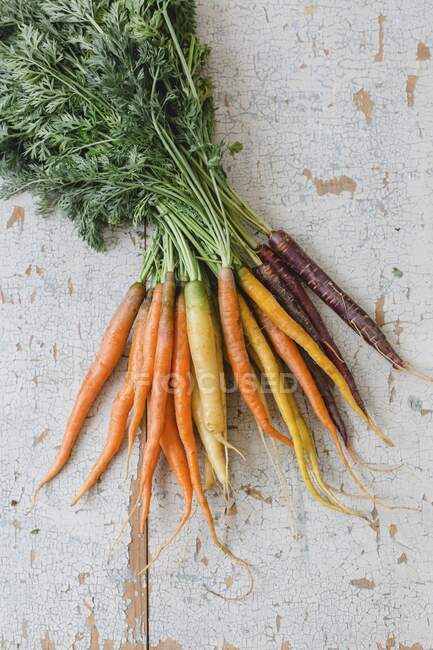 Un ramo de zanahorias frescas y coloridas sobre un fondo de madera blanca (vista superior)) - foto de stock