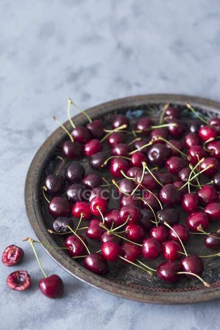 Fresh cherries on metal tray and on concrete surface — Stock Photo