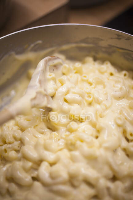 A cook preparing pasta and cheese sauce for making macaroni cheese — Stock Photo