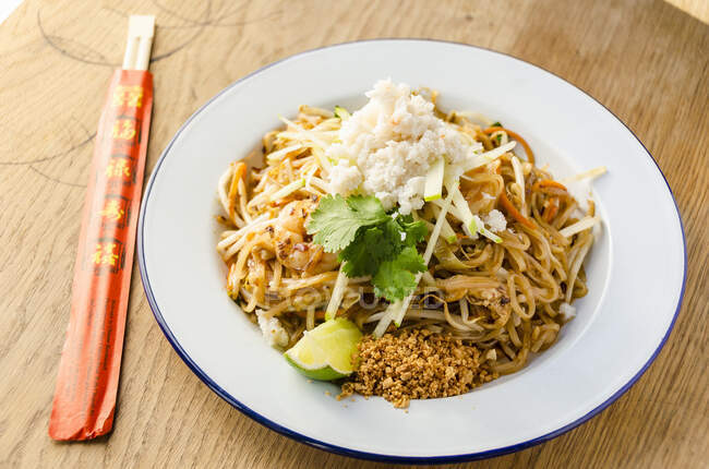 Pad thai stir fried noodles with prawns, chilli, beans, sprouts, spring onions, carrots, crab meat, shredded apple, lime and peanut — Stock Photo