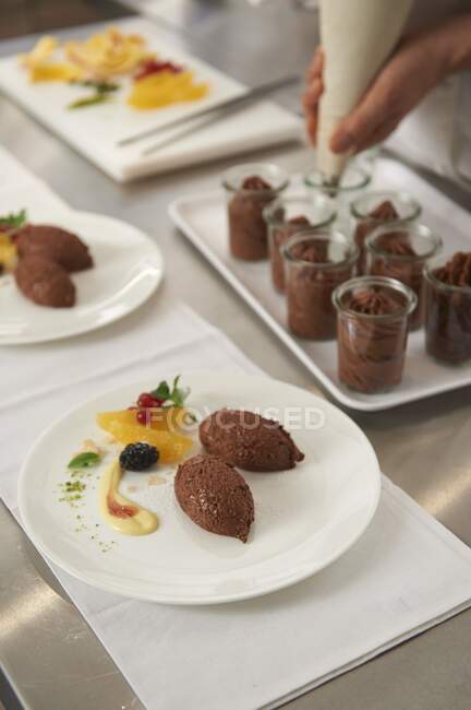 Chocolate mousse being piped into small glass jars — Stock Photo