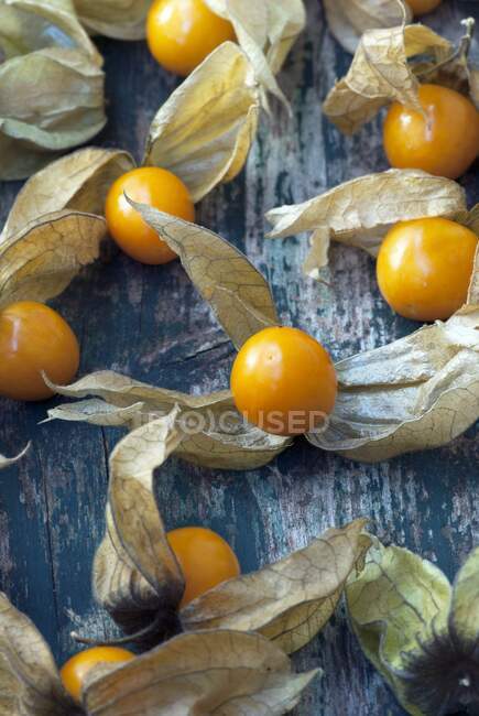 Bacche di Physalis fresche con foglie secche su superficie di legno — Foto stock
