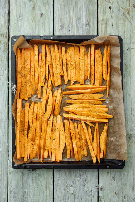 Sweet potatoes, peeled and sliced, on a baking tray — Stock Photo