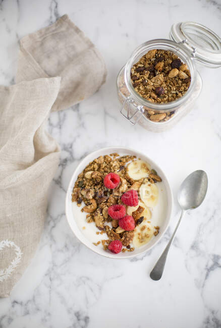 Granola with yoghurt and raspberries in bowl and jar — Stock Photo