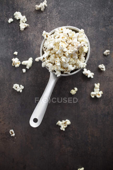 Popcorn in grande cucchiaio di ceramica e sul tavolo — Foto stock