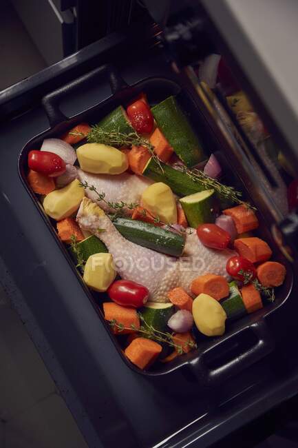 Pernas de frango com verduras em uma bandeja de cozedura — Fotografia de Stock