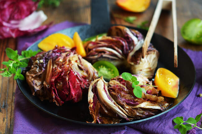 Fried radicchio salad with fresh tomatoes and herbs in pan — Stock Photo