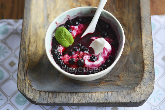 Yogurt with sugar and frozen blueberries on wooden tray — Stock Photo