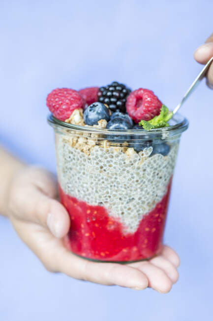 Hands holding chia pudding with berries and cereal — Stock Photo