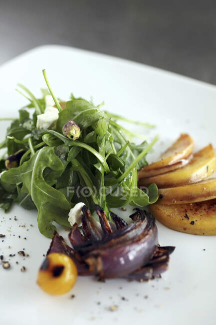 Arugula salad with grilled peach, grilled red onion, feta and pistachios — Stock Photo