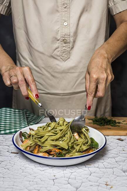 Une femme servant des tagliatelles vertes avec des fruits de mer — Photo de stock