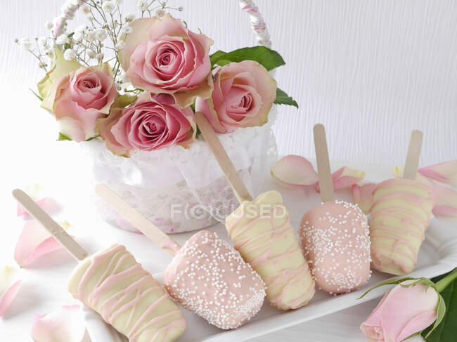 Cheesecakes on sticks with white and pink chocolate icing — Stock Photo