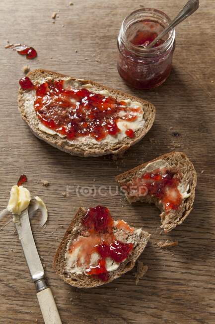 Two slices of fresh bread covered in butter and jam — Stock Photo