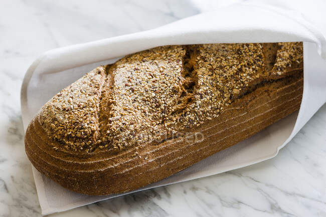 Un pane integrale rustico in un tovagliolo — Foto stock