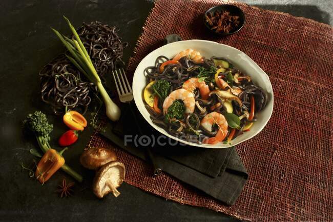 Shrimps and black noodles with chilis, mushrooms and vegetables — Stock Photo