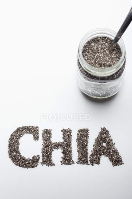 Chia seeds: in a glass jar and lettered against a white background — Stock Photo