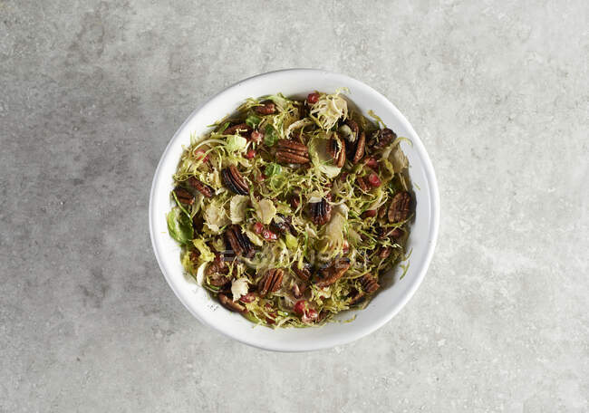 Grated brussels sprouts with maple syrup glazed pecans and pomegranate seeds — Stock Photo