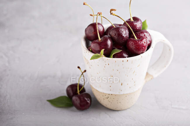 Cerejas doces frescas em uma caneca de cerâmica — Fotografia de Stock