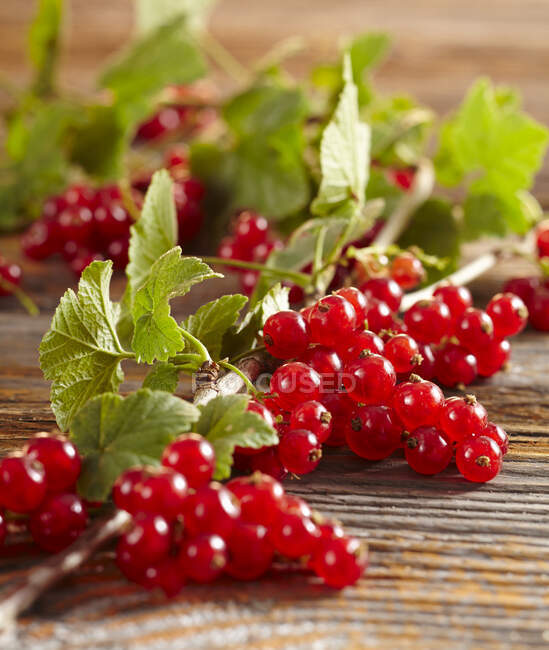 Fresh Redcurrants with green leaves on wooden surface — Stock Photo