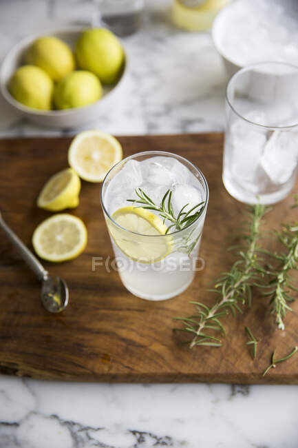 Gin and tonic with lemon and rosemary on wooden board — Stock Photo