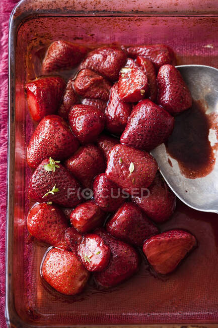 Caramelized strawberries in glass baking dish with spoon — Stock Photo