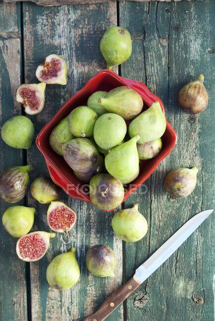 Fresh figs in red crate and on rustic wooden surface with knife — Stock Photo