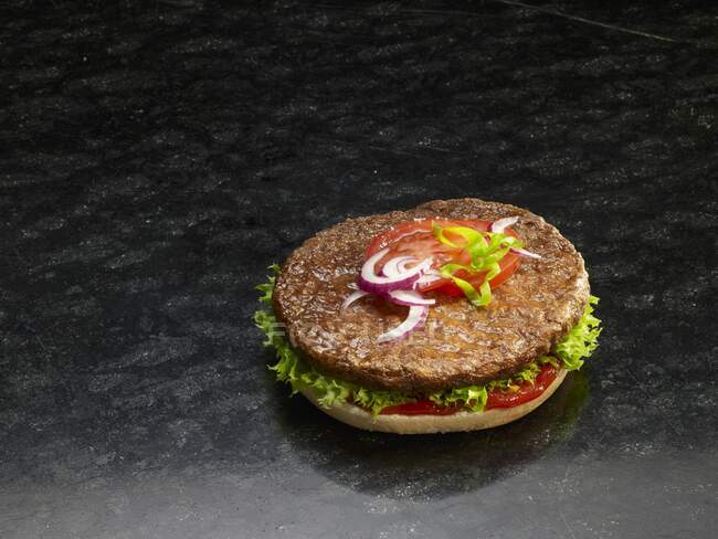 Close-up de delicioso hambúrguer em um pão de hambúrguer cortado pela metade — Fotografia de Stock