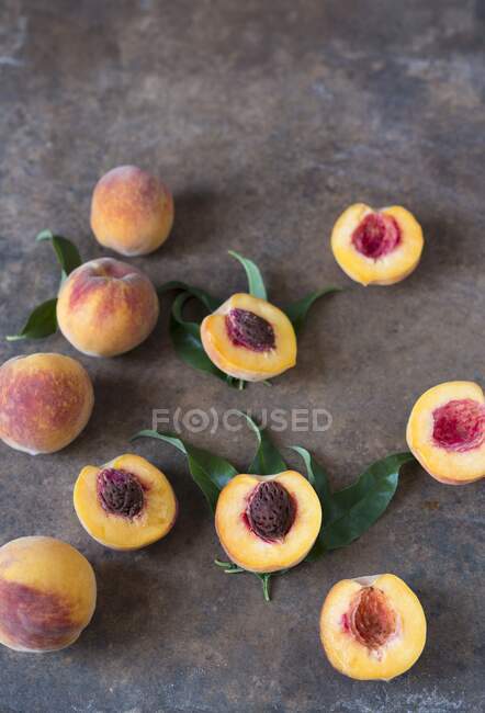 Peaches and peach halves on metal surface — Stock Photo