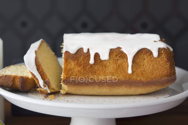 Rebanadas cortan un pastel de libra con glaseado de vainilla - foto de stock