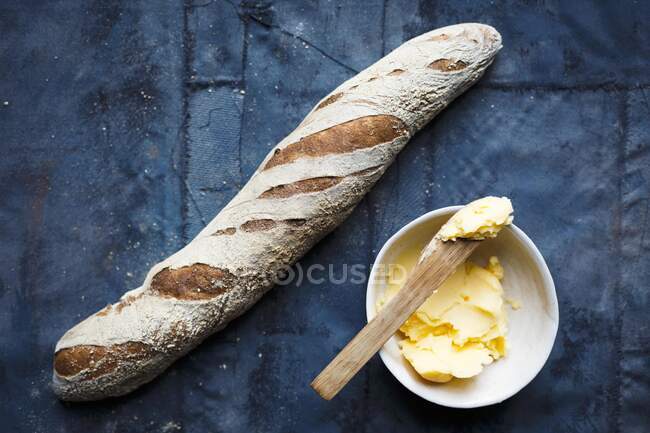 A baguette and a bowl of butter (top view) — Stock Photo