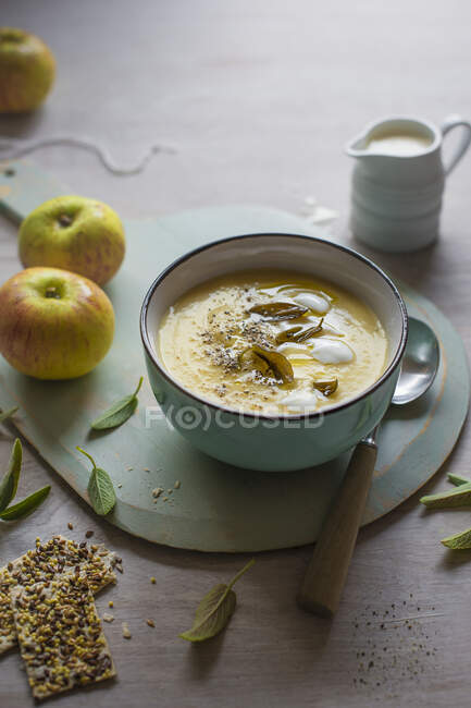 A bowl of celeriac and apple soup with sage and crackers — Stock Photo