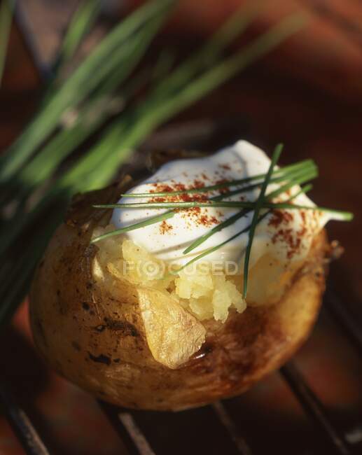 A baked potato with cream fraiche and chives — Stock Photo