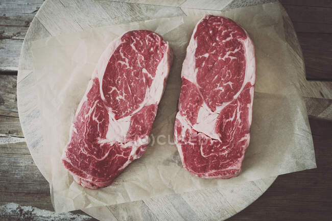 Biftecks de côtelettes crus sur un morceau de papier — Photo de stock
