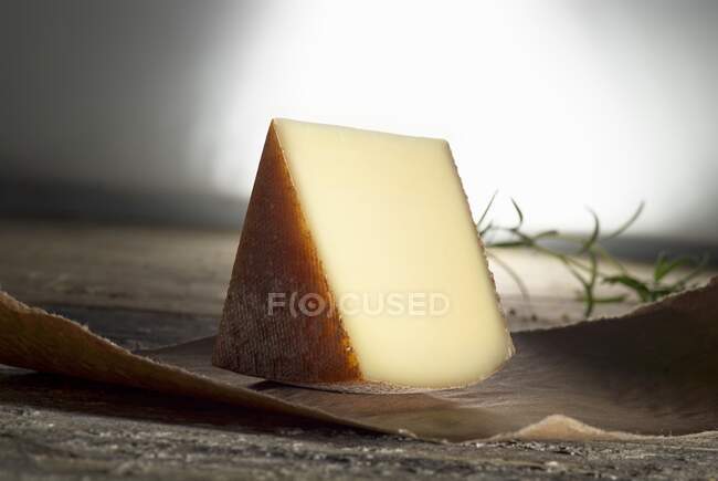 Altabadia hard cheese on paper with herb on background — Stock Photo
