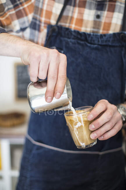 Man pouring milk in coffee, closeup — Stock Photo