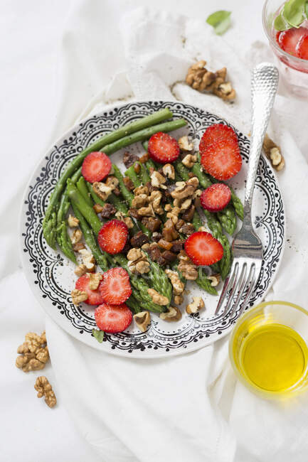 Green asparagus salad with walnuts and strawberries — Stock Photo