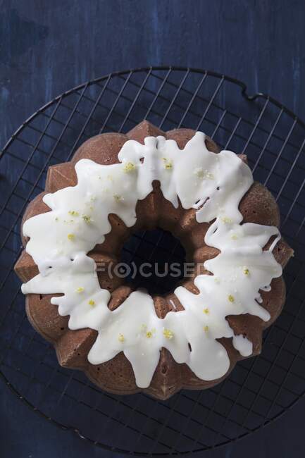 Orange ring cake with icing on a wire cooling rack — Stock Photo