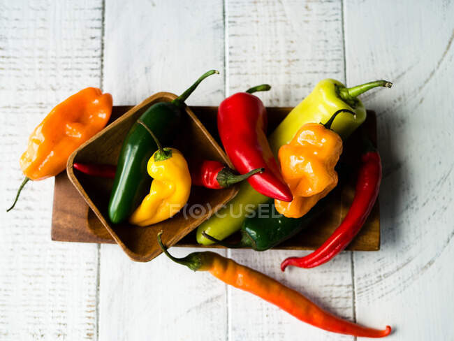 Various colourful chilli peppers in a wooden bowl — Stock Photo