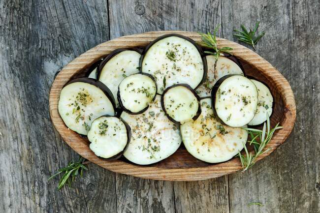 Eggplant slices with herbs in a wooden bowl — Stock Photo