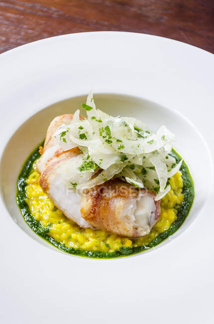 Sea bass fish fillet fricasee on a saffron risotto with wild fennel, basil, chilli — Stock Photo