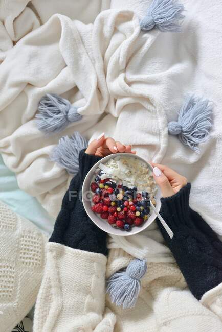 Woman holds a bowl of porridge and fruit in her hands — Stock Photo