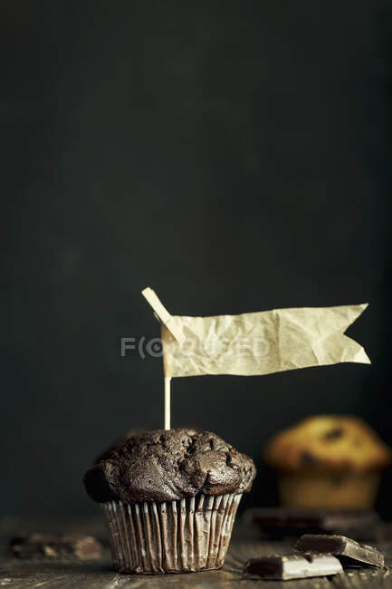 Muffin al cioccolato con bandiere di carta su sfondo scuro — Foto stock